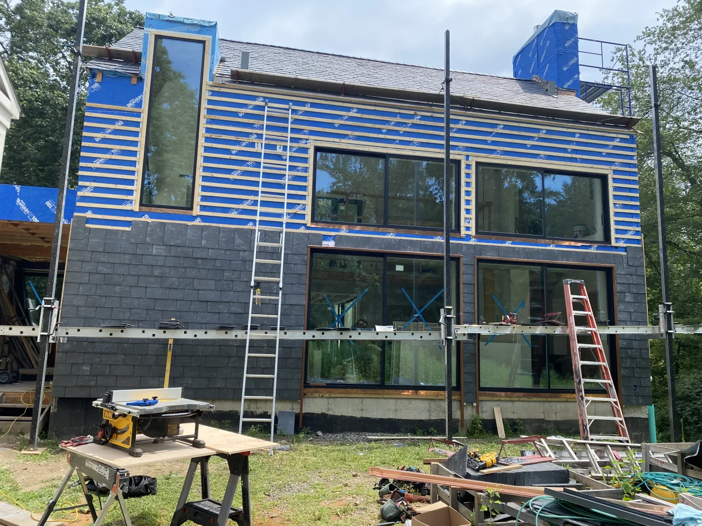 A Sound Renovation company vehicle near a dumpster as roof work takes place on a commercial building.