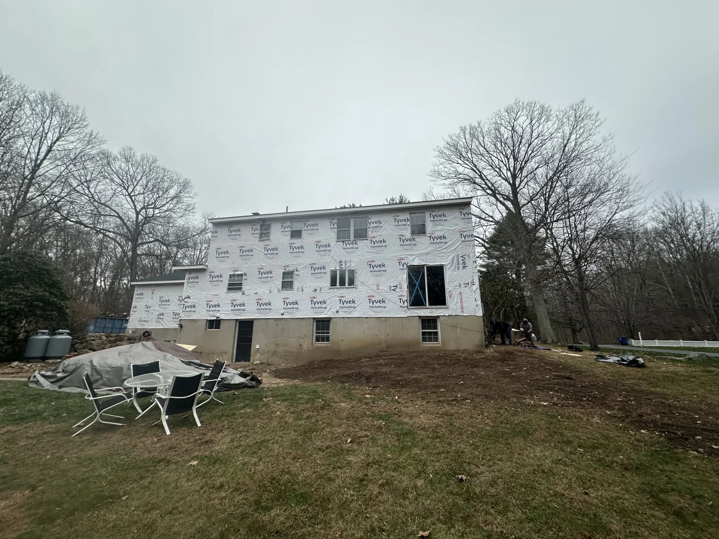 The rear view of a home that is in the process of having new siding installed on it.