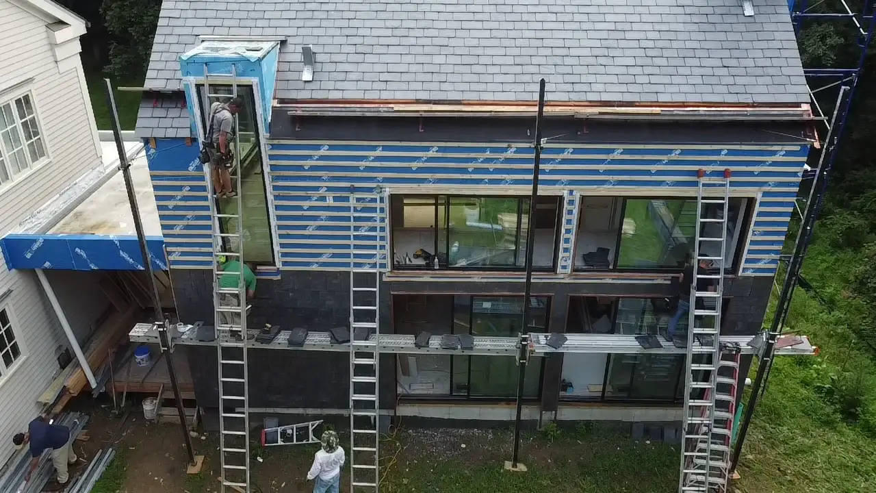 A home in the process of having new siding installed on it in a dark color for a modern look.