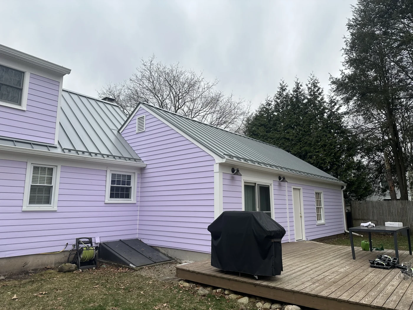 A light purple home with a new gray standing seam metal roof installed on it.