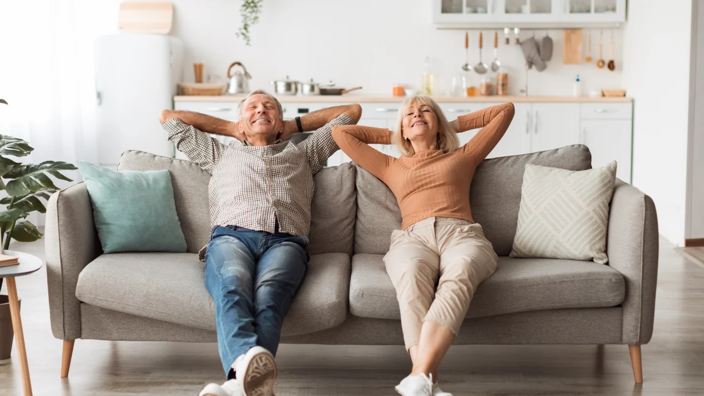Hassle-Free Exterior Services | Fairfield County, CT | Sound Renovation A frontal view of an older man and woman sitting on a couch, hands behind their heads and smiling.