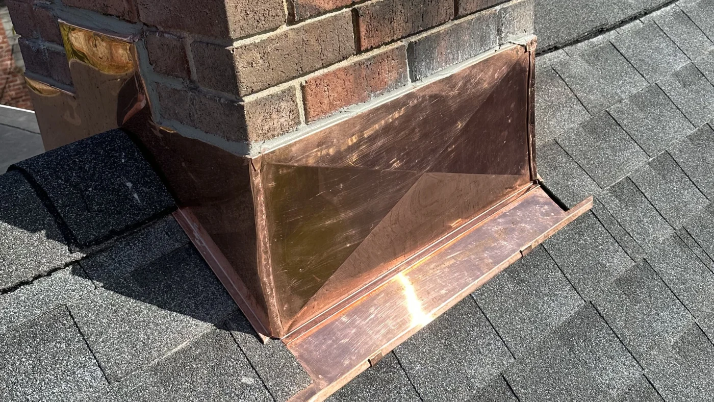 A close view of the custom copper chimney flashing installed on a local roof.
