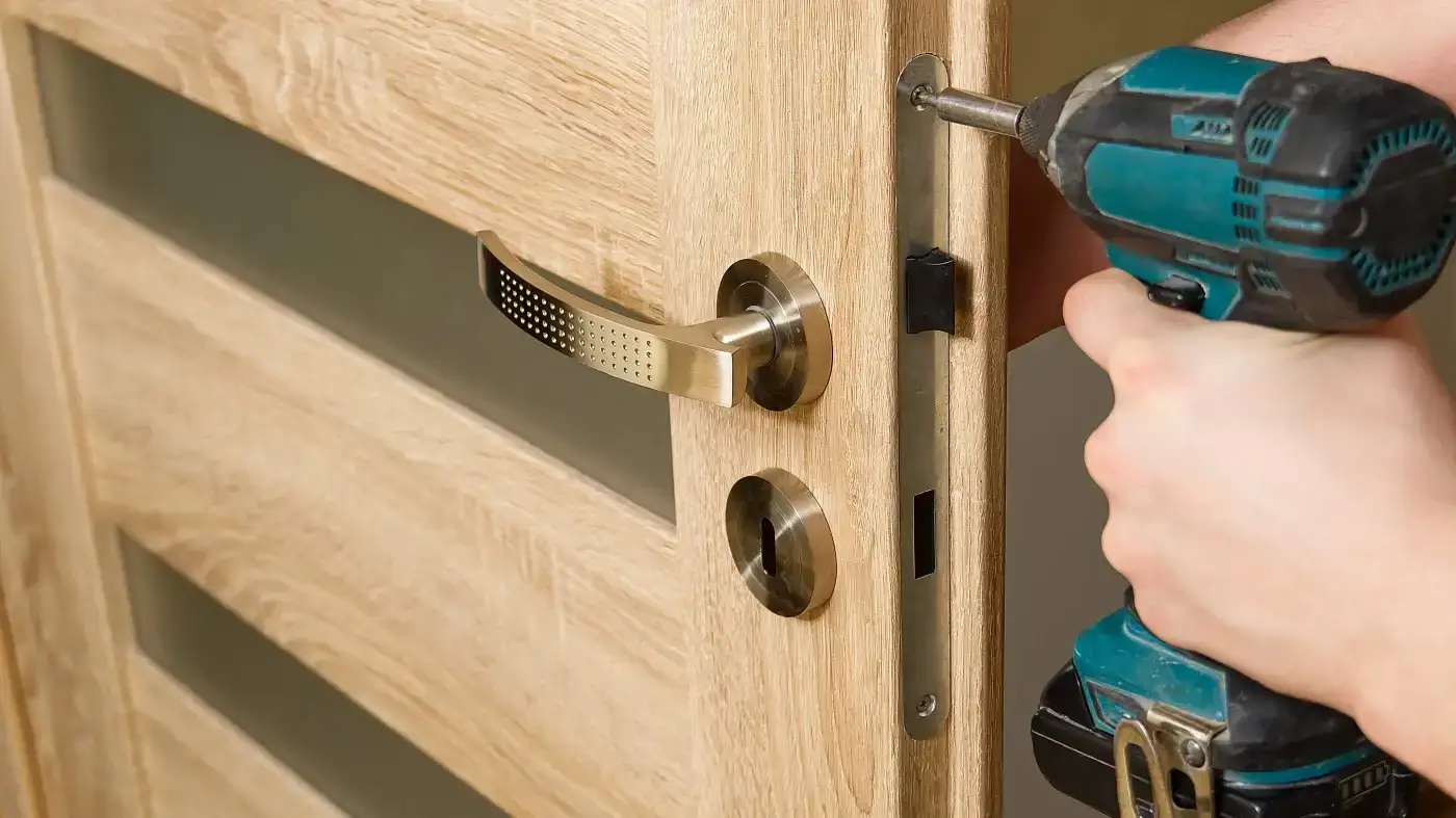 A close-up view of a man installing the hardware on a beautiful wood exterior door.