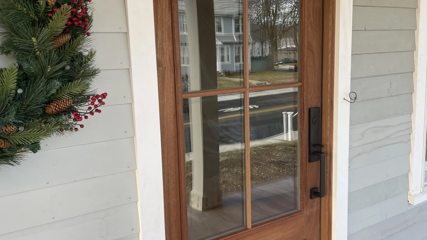 A close, angled view of a new wood front door installed in a local home by Sound Renovation.