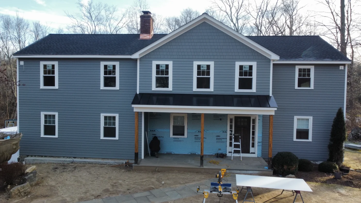 Superior Metal Roofing & Fabrication In Weston, CT | Sound Renovation A blue two-story home with a porch that has a standing seam metal roof.