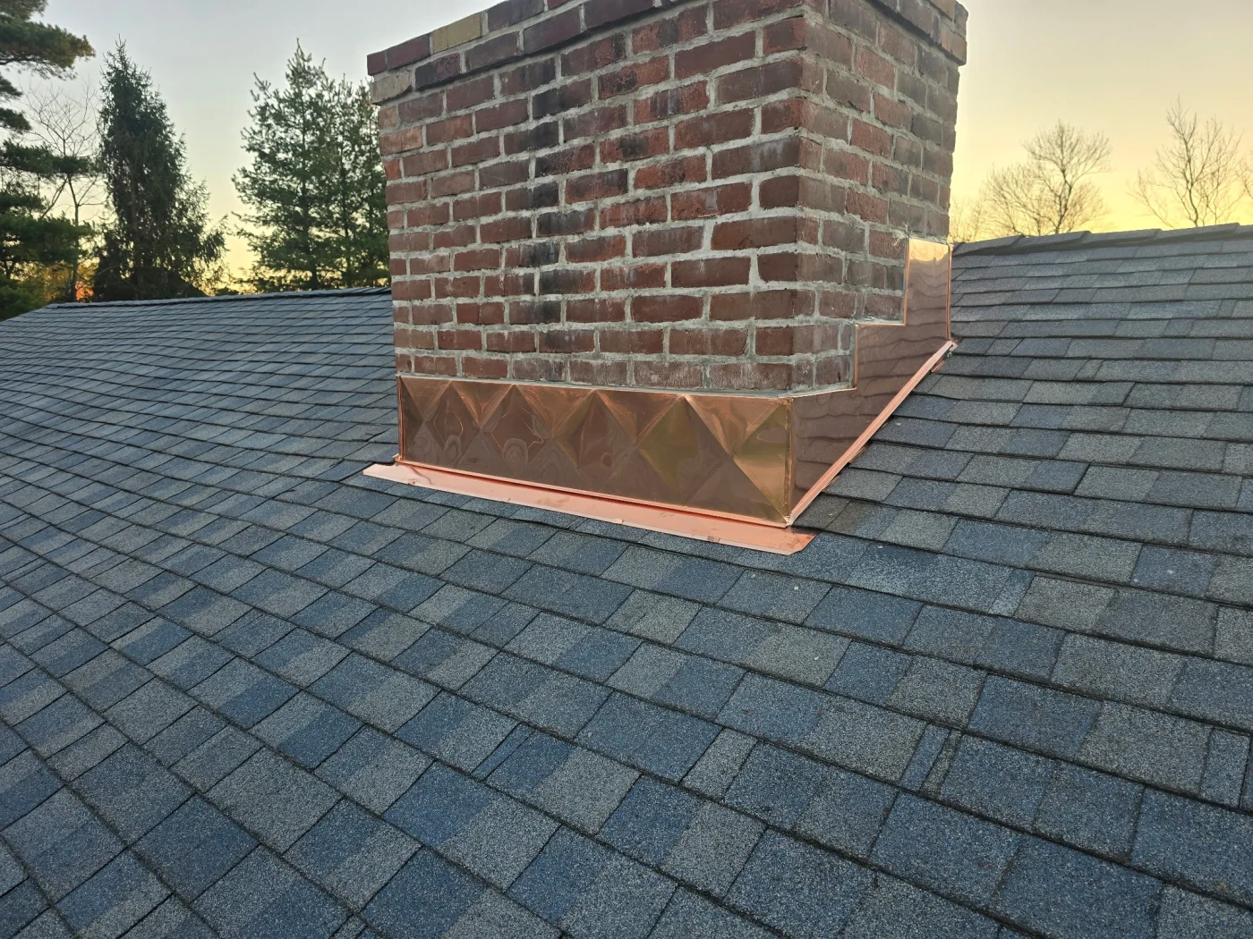 Targeted Residential Roof Replacement In Weston, CT | Sound Renovation A close-up view of a dark asphalt roof and the flashing around the chimney.