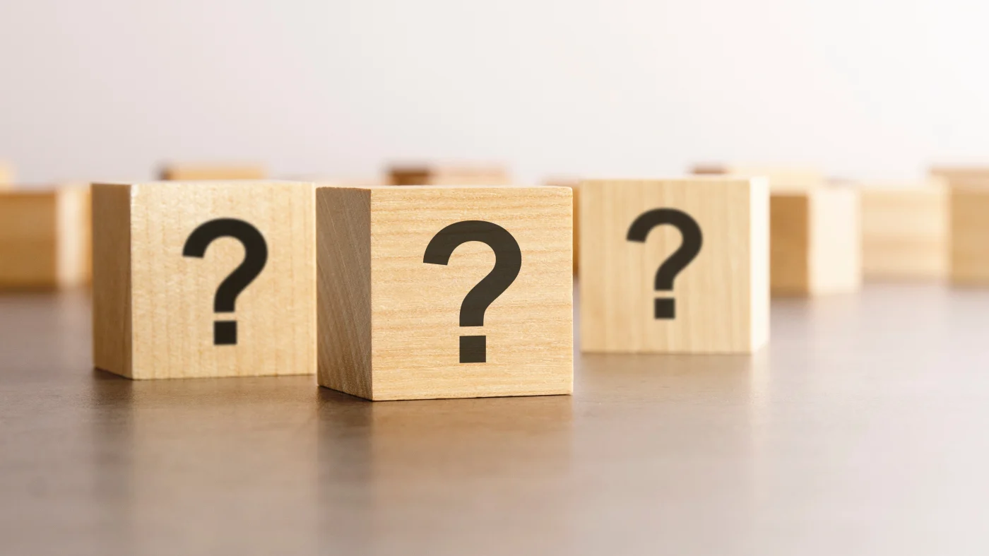 Top Exterior Services FAQs | Fairfield County, CT | Sound Renovation A close view of three small wooden blocks sitting on a large table; each of the blocks has a black question mark printed on it.