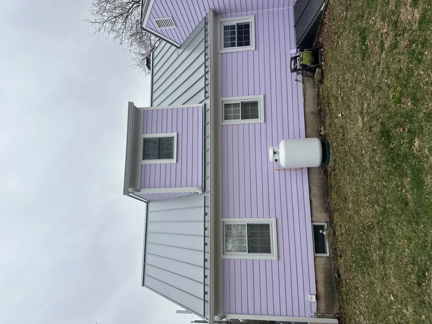 A home with lilac siding and a new metal roof installed.