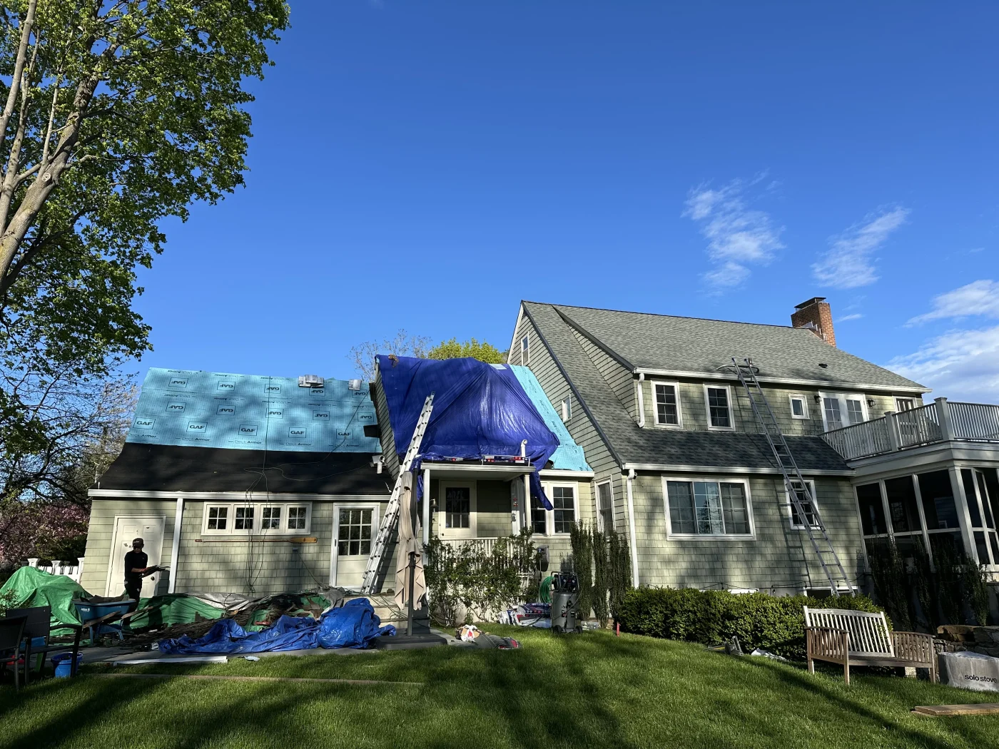 A two-story colonial-type home with tarps over it, awaiting a roof replacement.