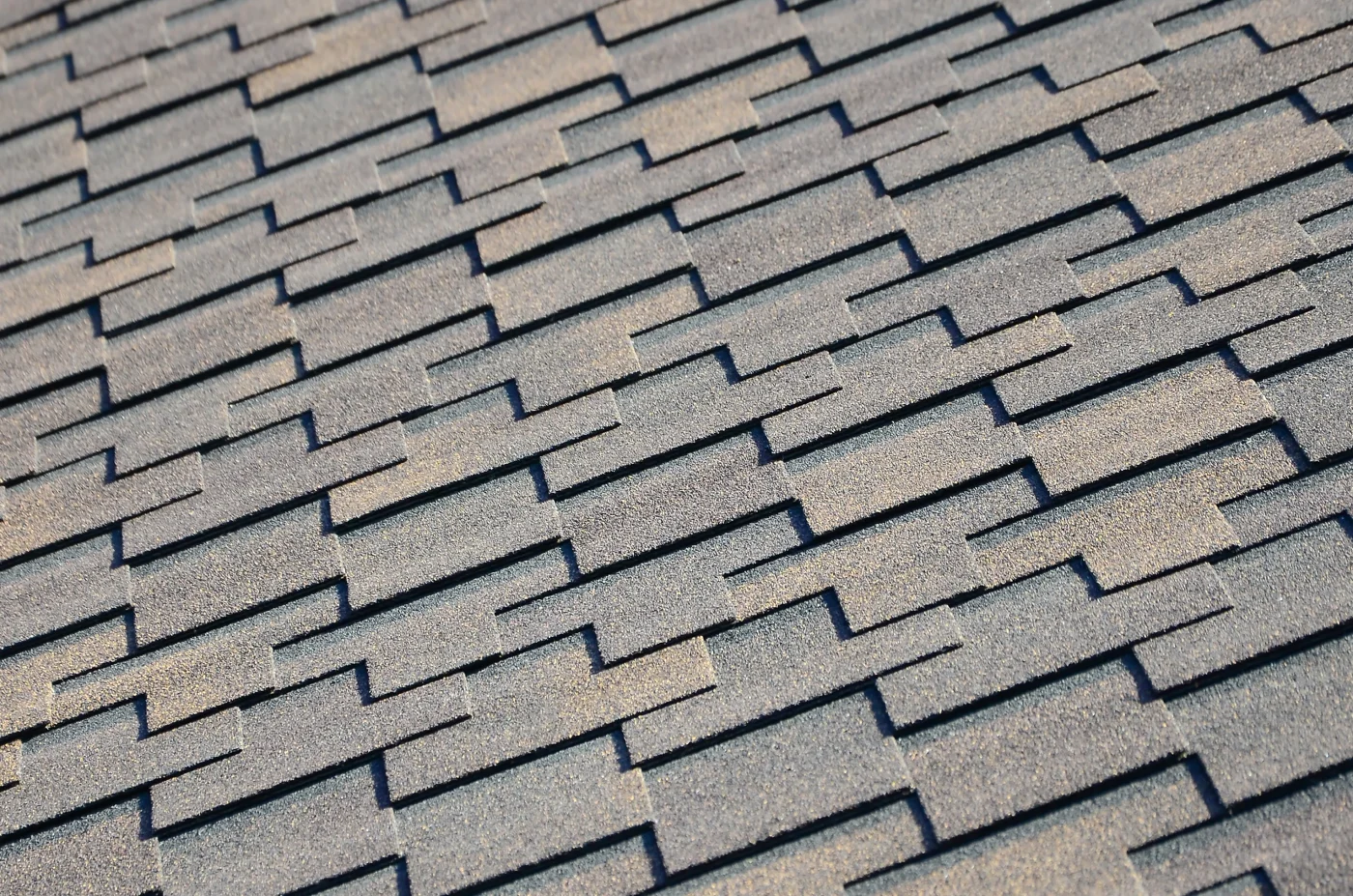A close-up shot of irregularly shaped asphalt shingles in various shades of brown.