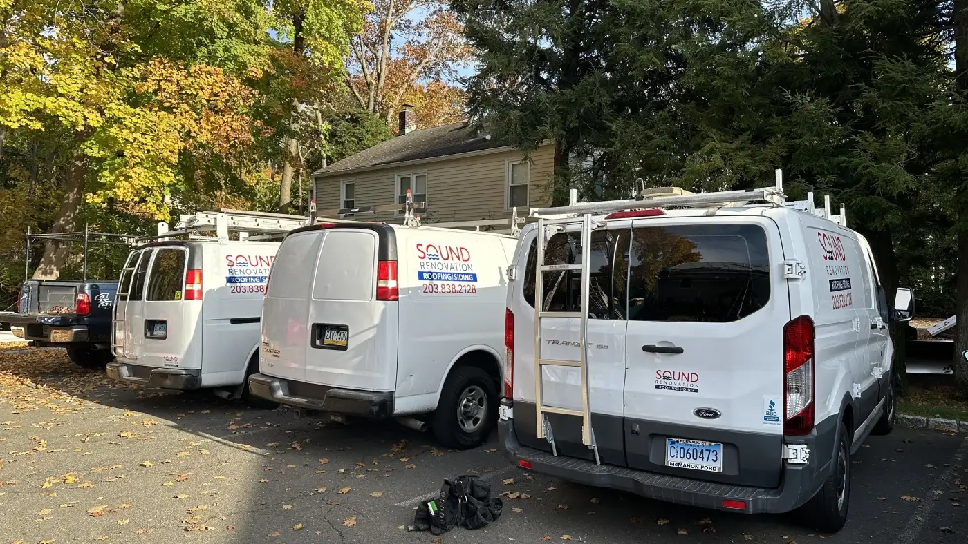 A wide shot of a line of Sound Renovation vans parked side by side in a parking lot.